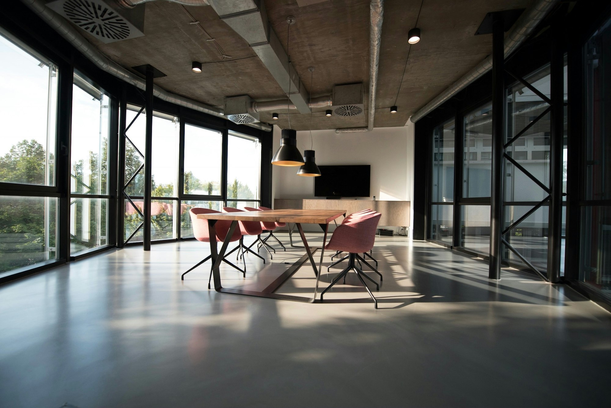 A bright, modern conference room with a long table and floor-to-ceiling windows